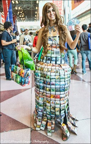 Abito lungo fatto con carte Magic, con in mano carte e una borsa della spesa