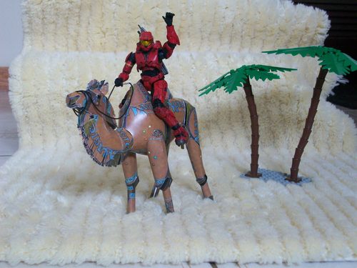 Diorama di un cammello nel deserto, con un personaggio giocattolo in sella