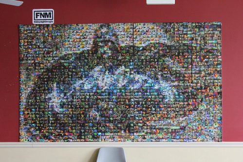 Grande mosaico appeso a una parete, composto da migliaia di piccole carte Magic